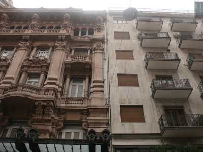 Foto 4. Svoltiamo in via Putignani e qui troviamo perlomeno tre grossi �pugni nell�occhio�. Il primo, ad angolo con via Sparano, mette insieme l'elegantissimo palazzo Mincuzzi in stile liberty, inaugurato nel 1928, color rosa antico e carico di decori e colonne ornate e uno spartano edificio con mattonelle grigie 